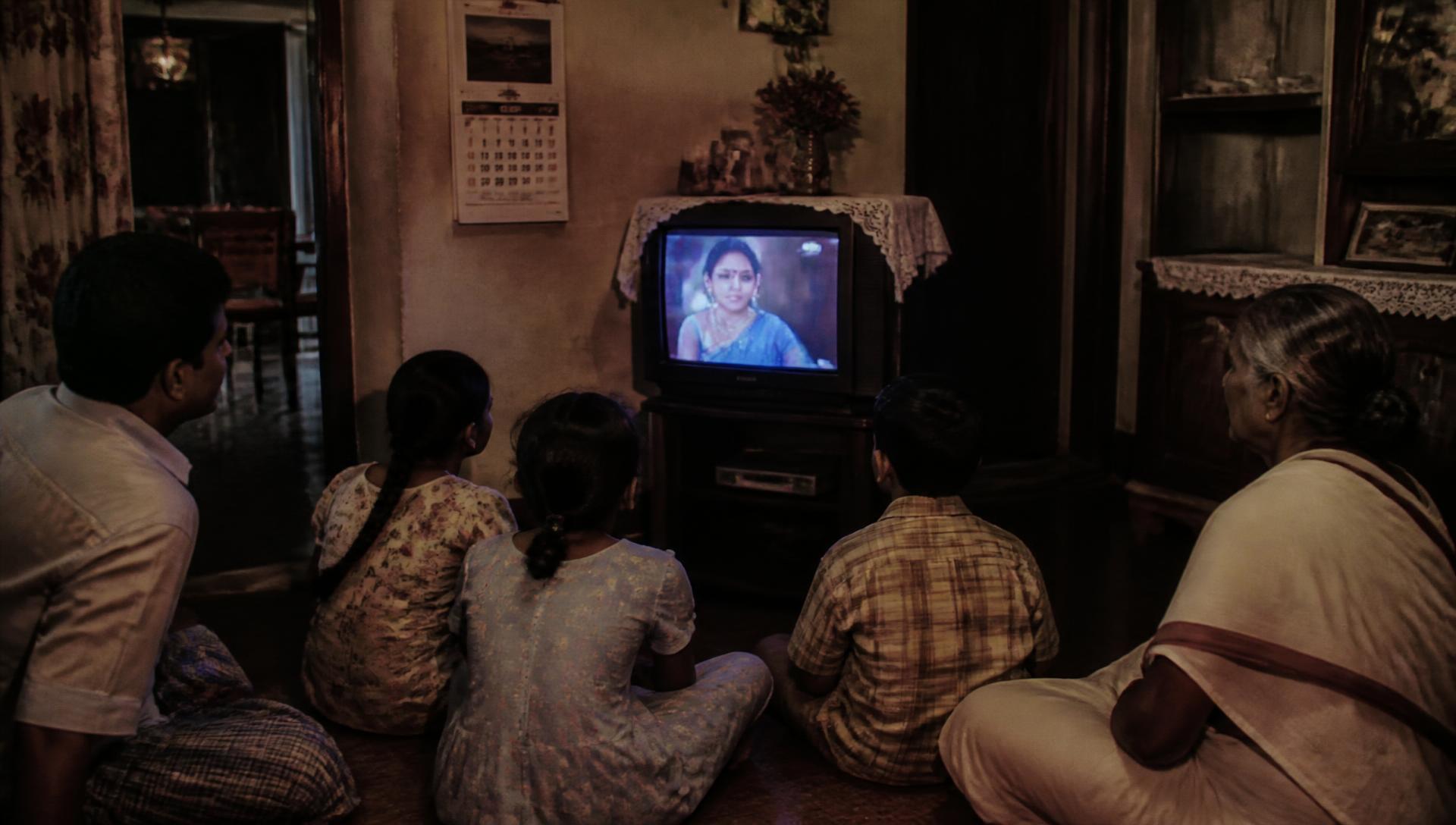 Family sitting around a CRT television in an old village house